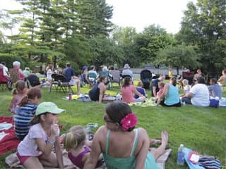 Families on picnic blankets listening to Music in the Park