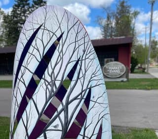 A painted Art Trail Tecumseh sculpture beside a downtown sidewalk